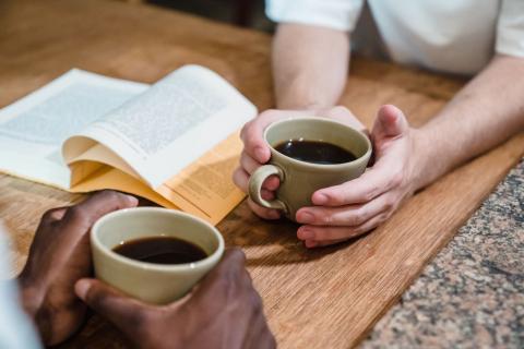 To personer med kaffe og en åben bog ved et bord