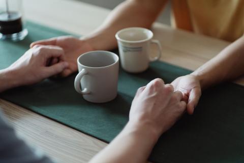 To par hænder om kaffekopper ved et bord