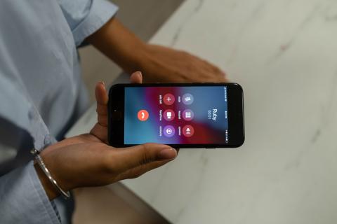 Hænder, der holder en telefon under et opkald