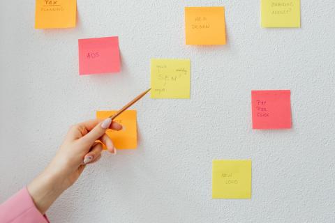 En hånd sætter sticky notes op på en væg